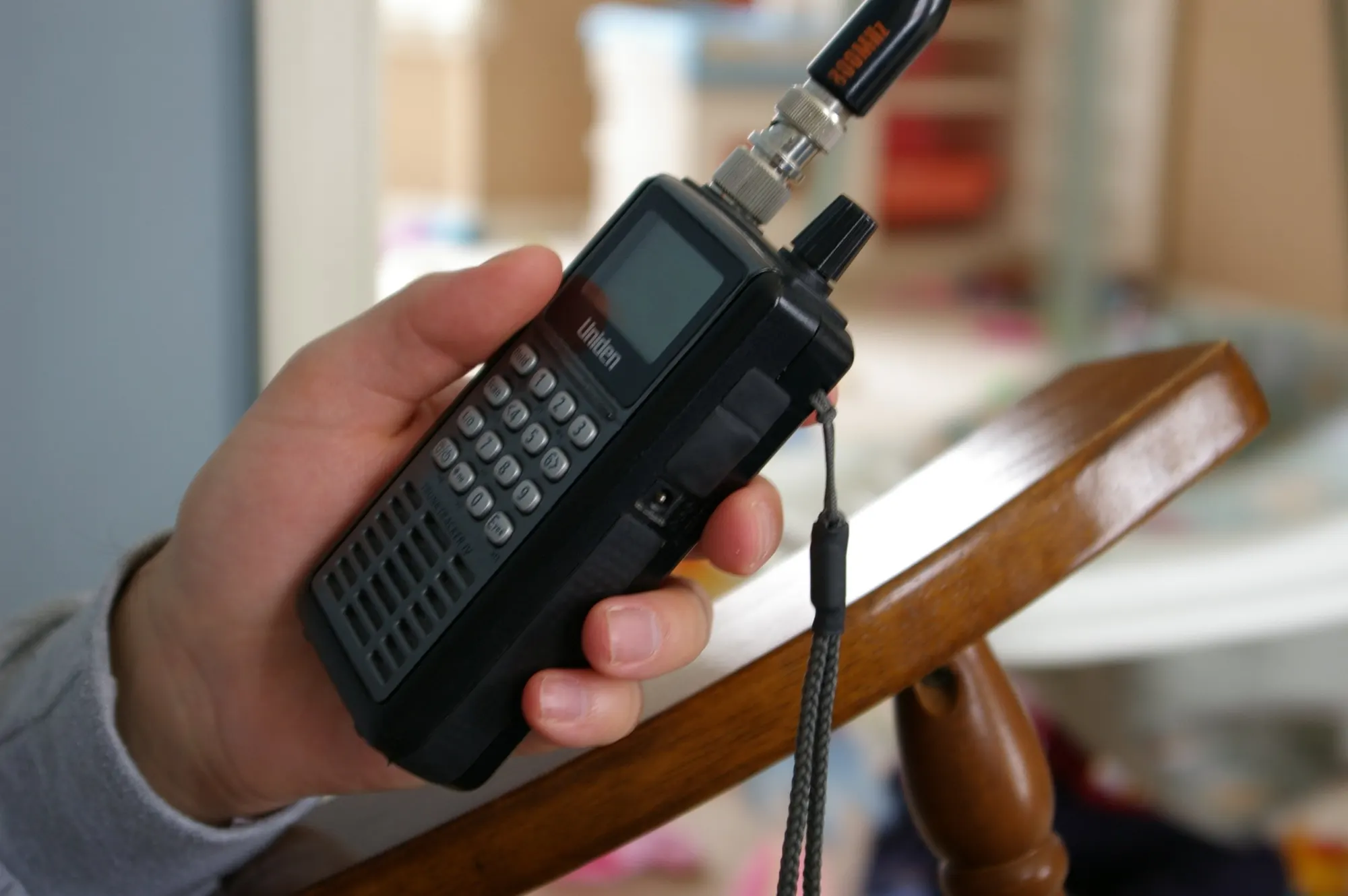A handheld Uniden digital scanner held in one hand